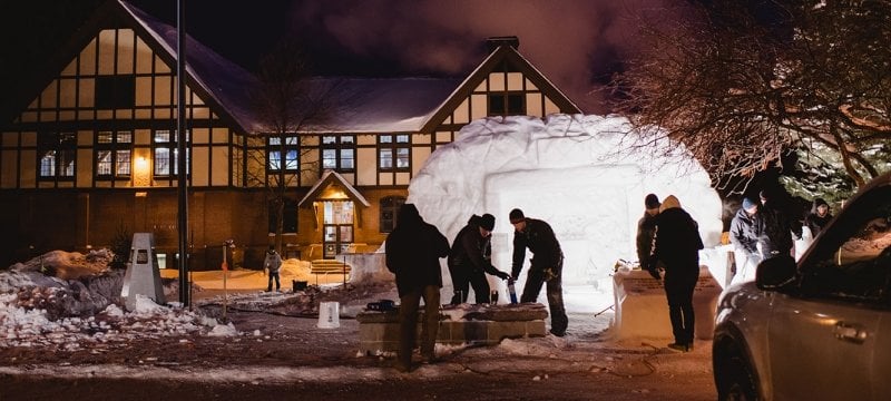 Students working on snow statue at night