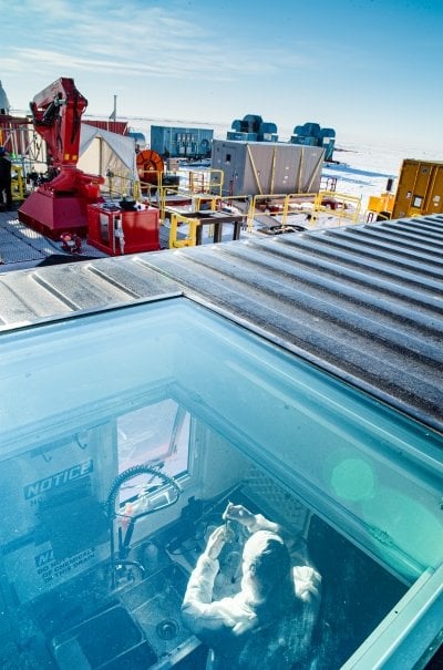 seen through through the glass roof of a mobile lab, a researcher works on gathering samples