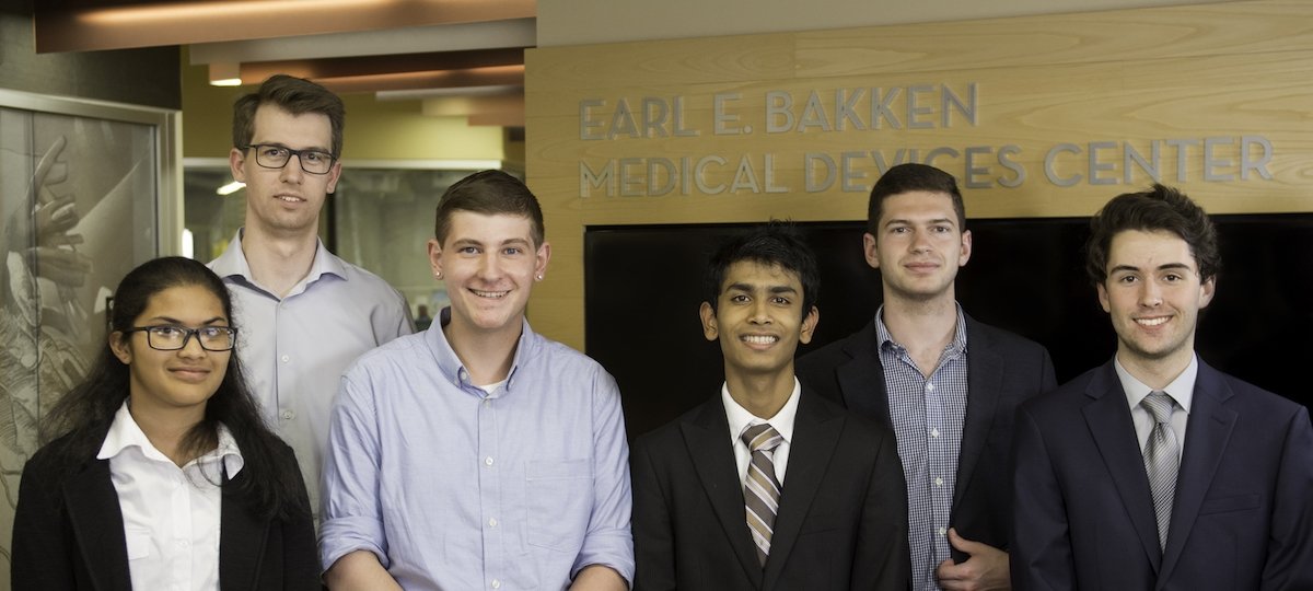 Jeremy Wales, third from left, and his fellow interns with their mentor in summer 2019. Six young people stand in front of a wall that says Earl E. Bakken Medical Devices Center