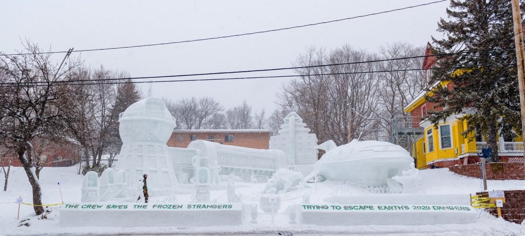 View of huge snow statue next to fraternity house