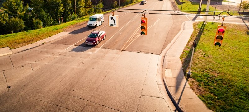 Cars stopped at a red traffic light on a sunny day.