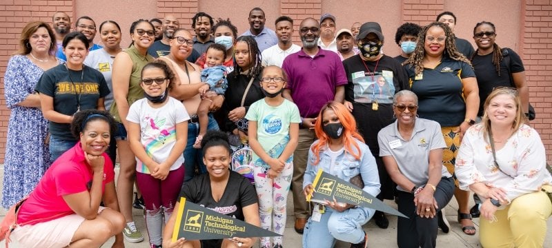 A group of Michigan Technological University Black alumni and prospective students pose for a group shot in front of a brick wall in Detroit's Greektown.