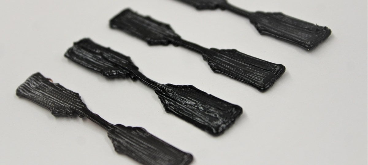Four 3D-printed dog-bone shaped ink samples on a surface.
