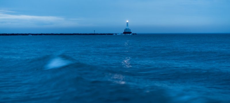 The North Entry light on the Keweenaw Waterway at dusk, with a wave breaking in the foreground.