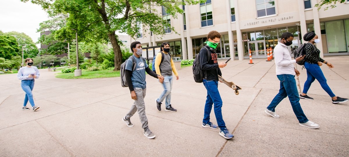 Students walk across Michigan Tech's campus while wearing face coverings.