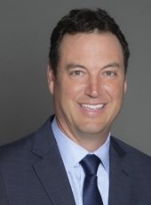 A man in a suit who is an MTU alumnus smiles in a portrait