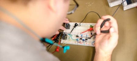 A student works up close on a circuit board.