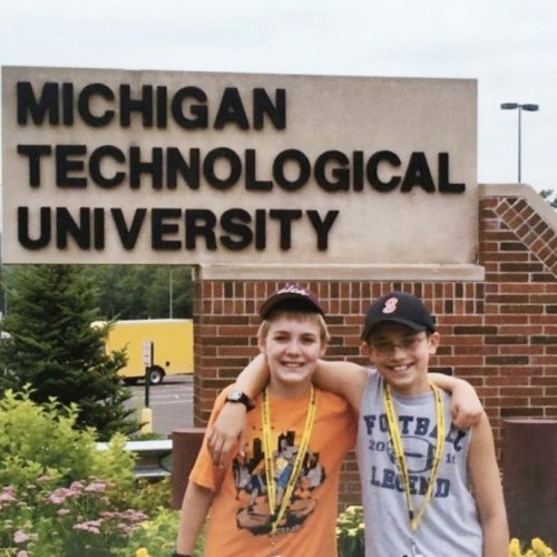 Two kids in front of the Michigan Technological University sign for Summer Youth Programs camp. They'd go on to attend Tech and graduate