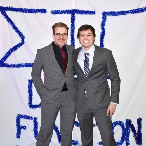 Two fraternity brothers stand in front of their Sigma Tau Gamma sign as they're inducted into MTU Greek Life.