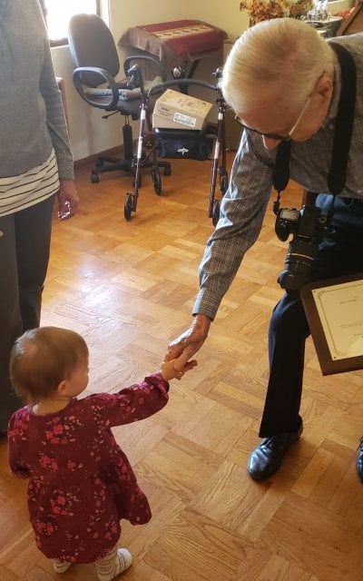 A little girl and an old man clasp hands, grandchildren of museum curators spanning 120 years.