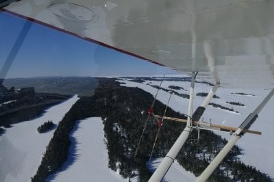 A seaplane flies over a snow and ice-covered national park out in Lake Superior