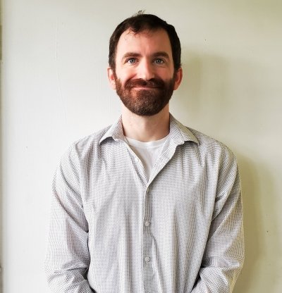 Award-winning doctoral candidate researcher Kevin Sunderland smiles in an indoor campus portrait.