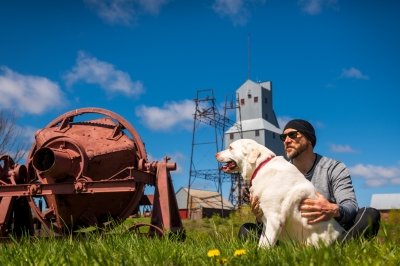 An energy policy expert and his dog sit on the lawn of Quincy Mine, the place where the researcher (while jogging with his dog) had an energy aha moment.