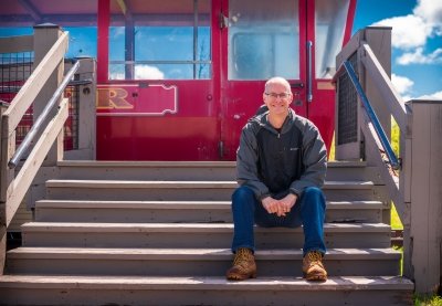 A researcher for pumped underground storage hydropower sits at the doors of an old tram car at the Quincy Mine site.