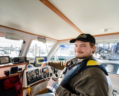 Captain Travis White of the Great Lakes Research Center smiles from the wheelhouse of the research vessel Agassiz anchored in the Straits of Mackinac.