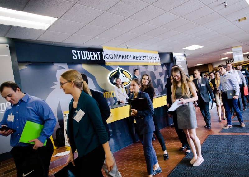 Studenci w garniturach, sukniach i innych strojach biznesowych ustawiają się w kolejce do kompleksu rozwoju studenckiego Michigan Tech for Career Fair.