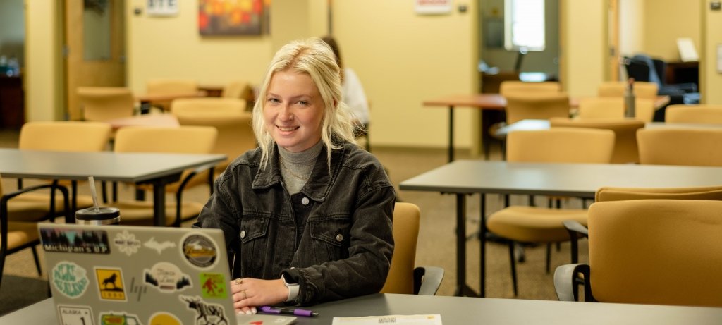 A Career Services student coach sits in the commons area with her laptop ready to help fellow students get ready for Career Fair