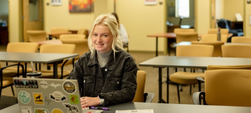 A Career Services student coach sits in the commons area with her laptop ready to help fellow students get ready for Career Fair 