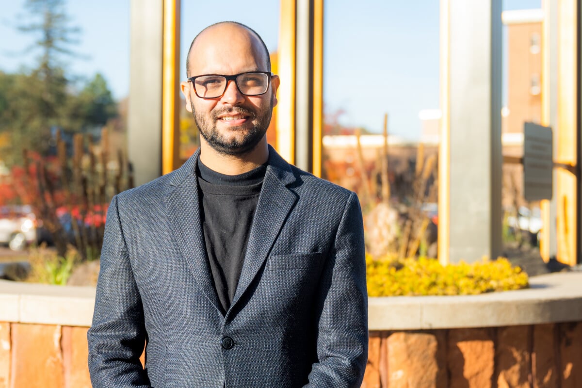 A delegate from MTU to the UN Climate Change conference poses by the clock tower outside on campus