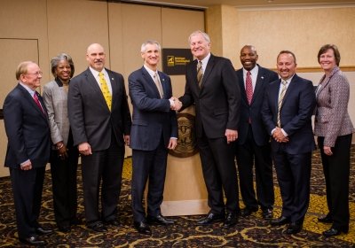 Michigan Tech's incoming and outgoing presidents shake hands as the selection committee stands by.