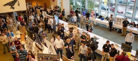 A crowd of students and guests looking at their projects throng around tables at the Design Expo 2023, where undergraduate projects are on display for the public and judges each year as part of Michigan Tech's commitment to hands-on learning.