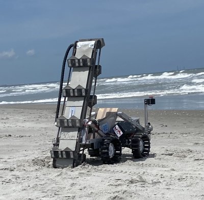 A lunabotics rover built by Michigan Tech undergrad students on an Atlantic beach with waves in the background after a lunar mining competition.