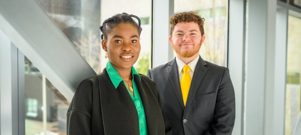 Graduating Huskies Tinu-Ololade Folayan, left, and Anderson Piercey give their advice on living your best life at Tech. The graduate and undergraduate student speakers for spring commencement smile in the sunny walkway between Rehki Hall and the Library