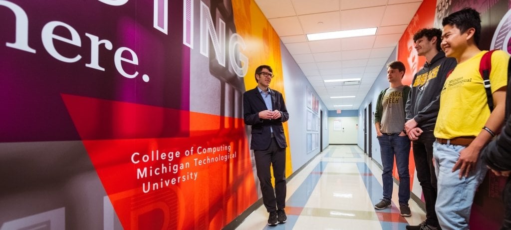 Michigan Tech's College of Computing and Institute of Computing and Cybersystems students and dean stand in the hallway of the college as a precede to an upcoming fall 2023 AI showcase.