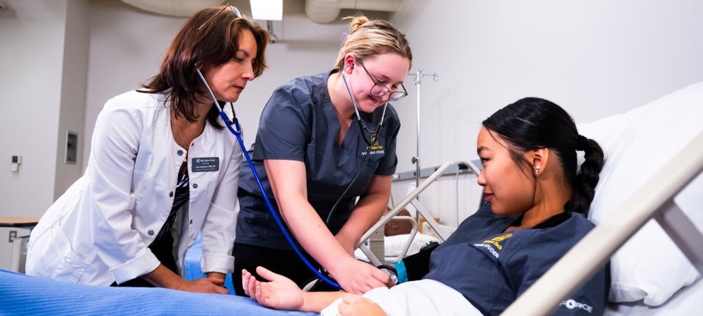 A nursing instructor works with two nursing students in the four-year program at Michigan Tech.