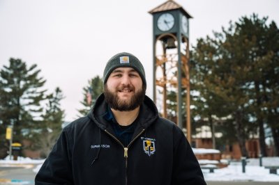 Joe Dlugos smiling in front of clocktower.