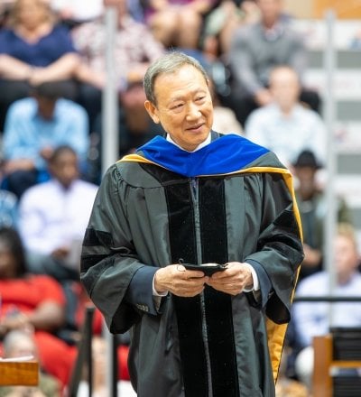 Chang Park stands in commencement regalia with Board of Trustees' Silver Medal