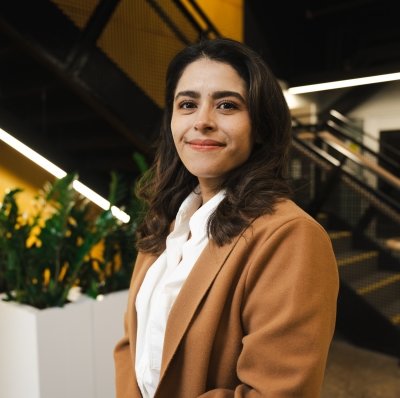 Michigan Tech's graduate commencement speaker for 2024, Zazil Santizo-Huertes, smiles in a portrait with the staircase of Michigan Tech's new H-STEM building in the background.