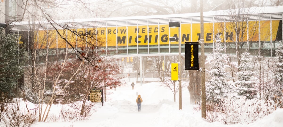 Michigan Tech is home not only to large amounts of snow, but expansive and unique snow research. In winter, snow covers the ground under the raised, enclosed walkway between Van Pelt and Opie Library and Rekhi Hall, with signage reading “Tomorrow Needs Michigan Tech.”