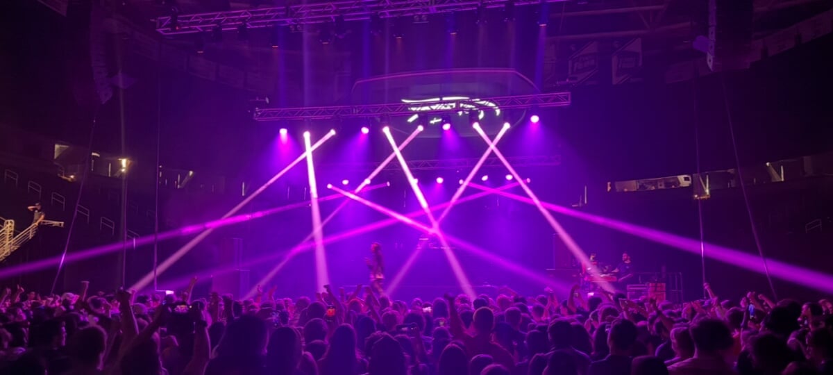 Visual and Performing Arts alumni Charles Southward, Dave Peterson and Steven Green are working hard in the audio industry — touring with major artists and designing sound for BAFTA award-winning video games. (Image courtesy of Dave Peterson) A concert venue filled with people and lit with bright purple beams from multiple stage lights.