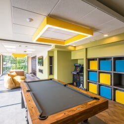 East Hall gaming room with pool table, arcade games, lounge seating, and large windows.