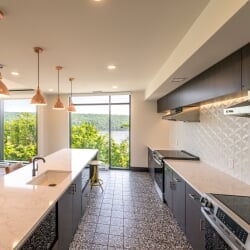 Communal kitchen in East Hall with modern appliances, counters, and large windows overlooking the Portage Canal.