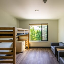 East Hall private single room with loftable bed, desk, dresser, and seating area.