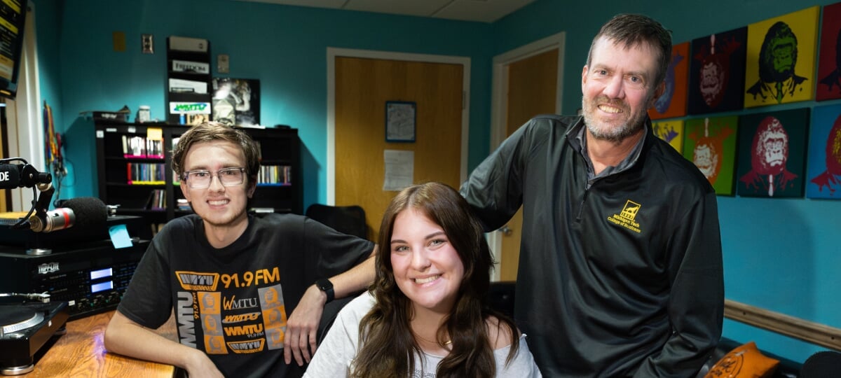 From left, College of Business Huskies Colten Baran, Roger Woods, and Veronica Frystak, hanging out in the WMTU DJ booth, personify the crossover between the classroom and campus radio. Two Michigan Tech students and their classroom instructor together in the WMTU DJ booth.