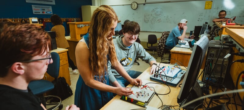 Paniz Hazaveh helps two students wire a circuit board in the lab.