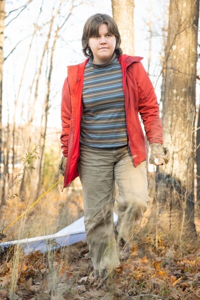 Grace Moeggenborg walks through a fall woodland, dragging a cloth behind her.
