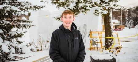 Andrew Hemstreet stands in front of a snow statue construction site.
