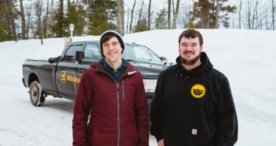 Ben Kopec and Nick Yeager standing in front of a GLRC truck with a large snowbank behind it.