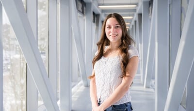 Ashley Baird standing in the bridge between Rekhi Hall and the Library.