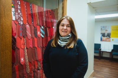 Laura Sieders standing next to the red tie display in the College of Business.