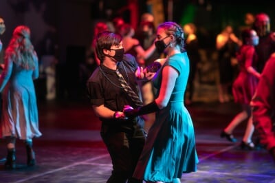 Two Michigan Tech students wearing protective face masks swing dance at the SnoBall.