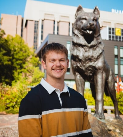 Jim Brisson standing in front of the Husky Statue.