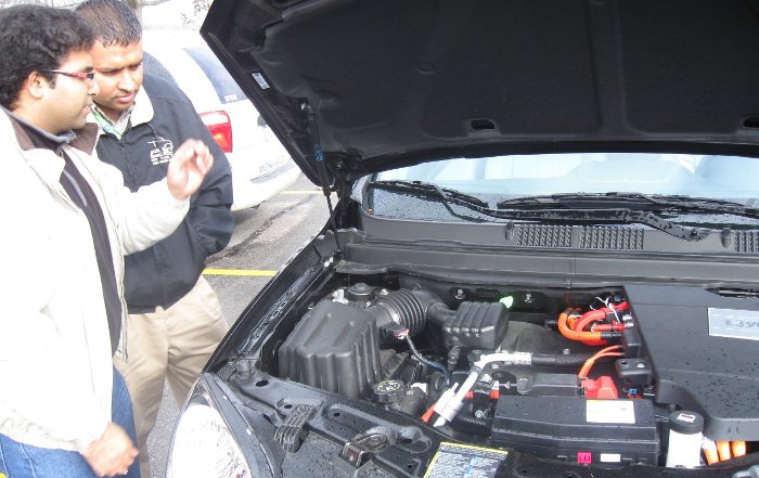 Teaching assistant Abhishek Manekar (left) points out some of the differences under the hood of a hybrid.    