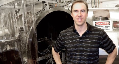 Associate Professor Brad King stands by a Space Simulation Vacuum Chamber