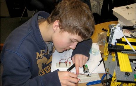 High School Enterprise Chassell High School student Jared Jarvi working on the wiring of a "bread board" for a light sensor array. Part of INANO's Lego model is shown.