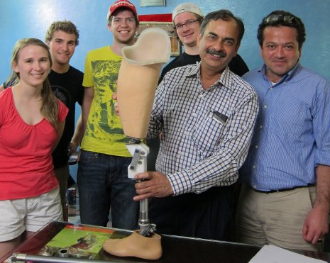 The senior design team holds the prosthetic knee they developed, attached to an artificial leg.